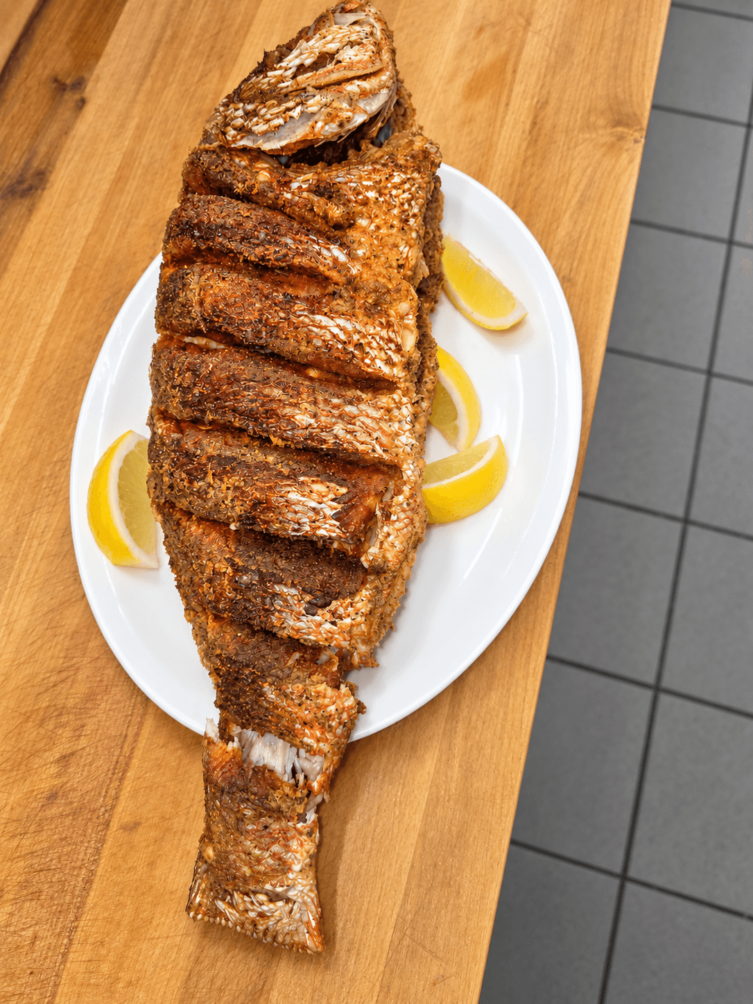 Whole fish served on a wooden board.