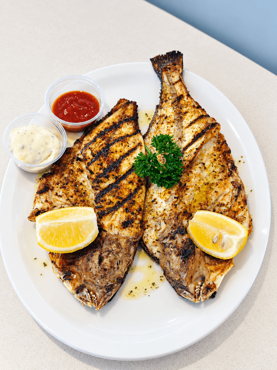 Whole grilled fish served with lemon and sauces.